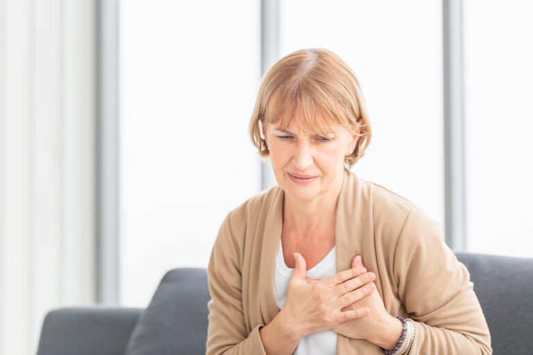 Senior woman with pain on heart in living room, Mature female pr